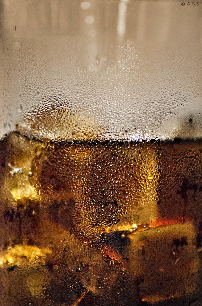 Close-up photograph of clear bubbles rising through a dark fizzy drink